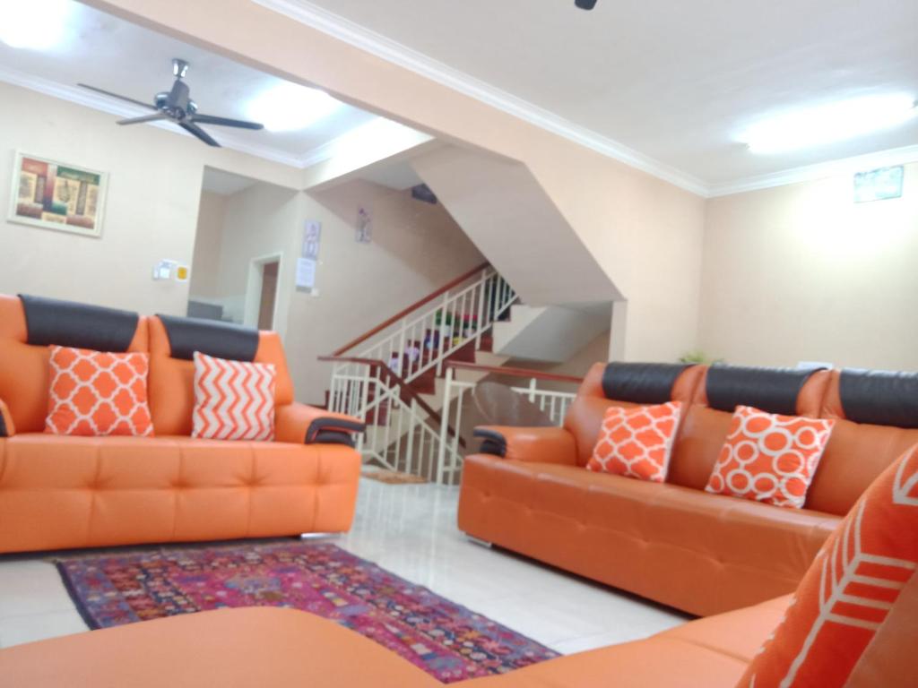 a living room with two orange couches and a staircase at Cosy P6 Homestay in Puchong