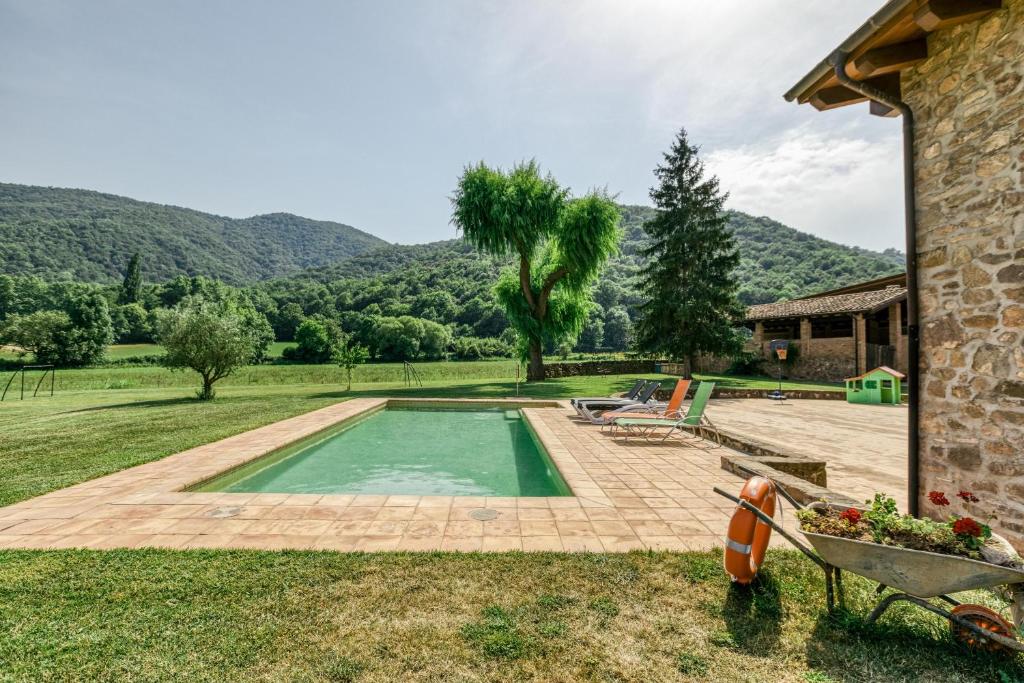 una piscina en un patio con montañas al fondo en Casa rural Mas Plantalech, en Vall de Bianya