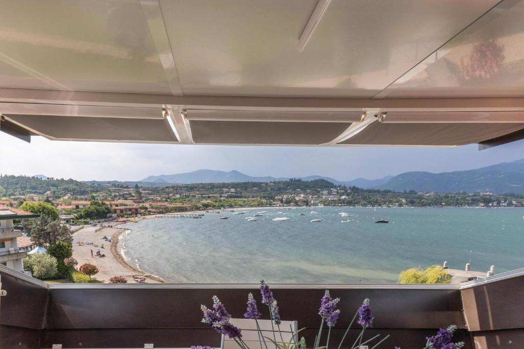 Residence Gigi Complex Manerba في مانربا ديل جاردا: غرفة مطلة على الشاطئ والقوارب في الماء