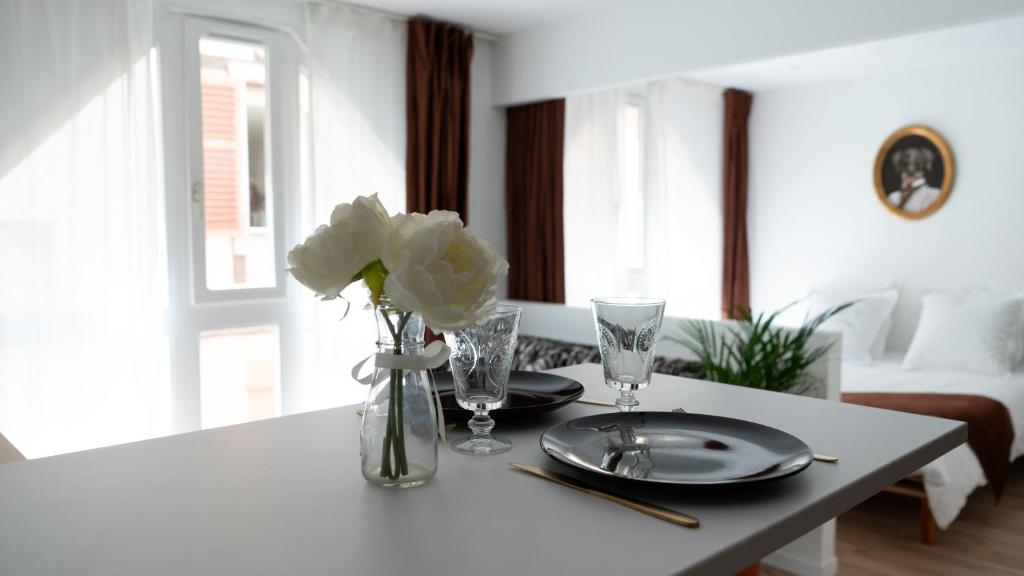 a table with two plates and a vase of flowers at LITTLE MAMA including free parking at 100 meters in Colmar