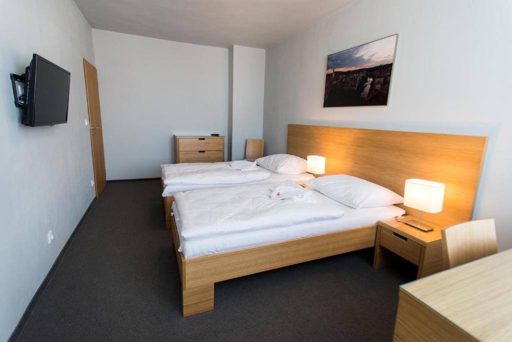 a hotel room with two beds and a television at Hotel Atom Třebíč in Třebíč