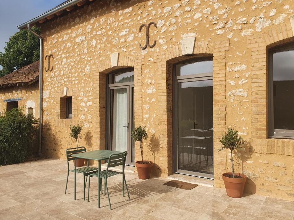 un patio con mesa y sillas frente a un edificio en Chambres d'hôtes de La Vallée, en Mansigné