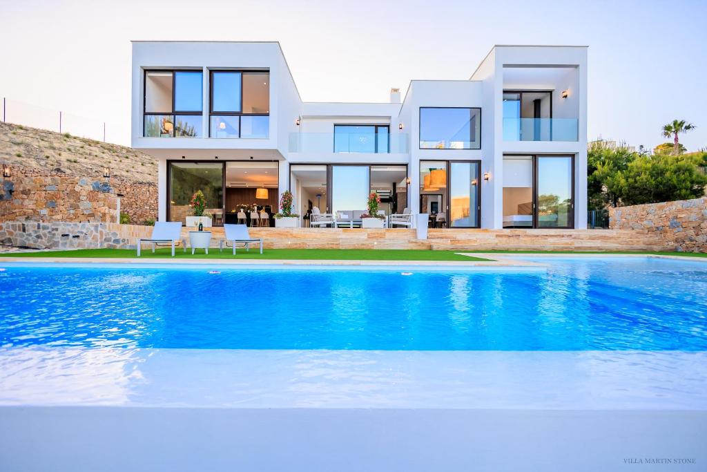 una villa con piscina frente a una casa en Villa Martin Stone- Las Colinas Golf Country, en Orihuela Costa