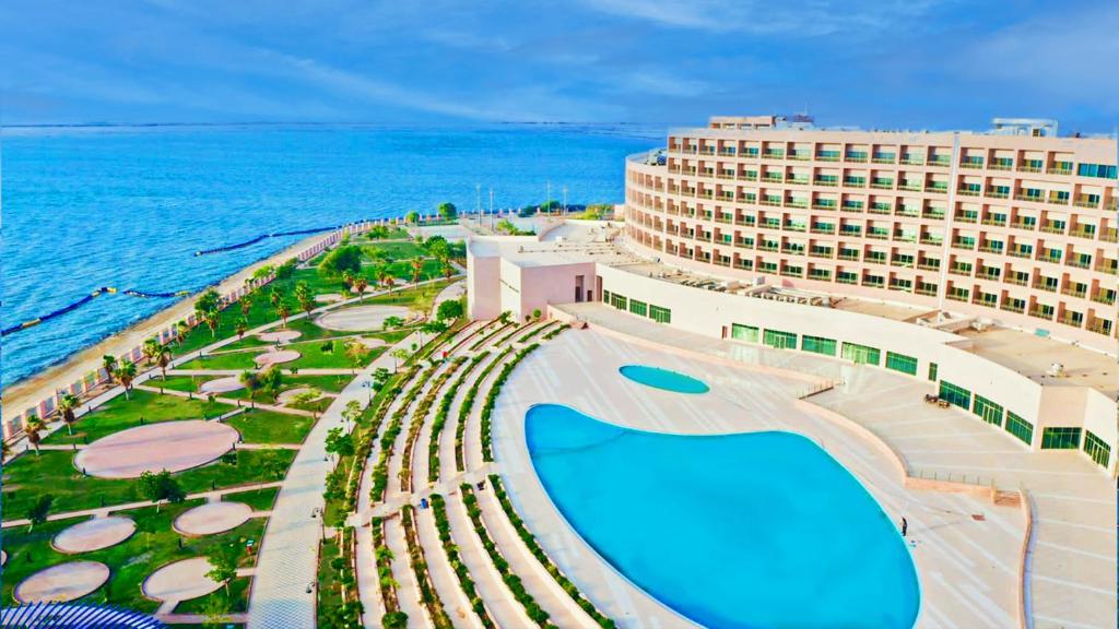 a building with a swimming pool next to the ocean at Grand Millennium Gizan in Jazan