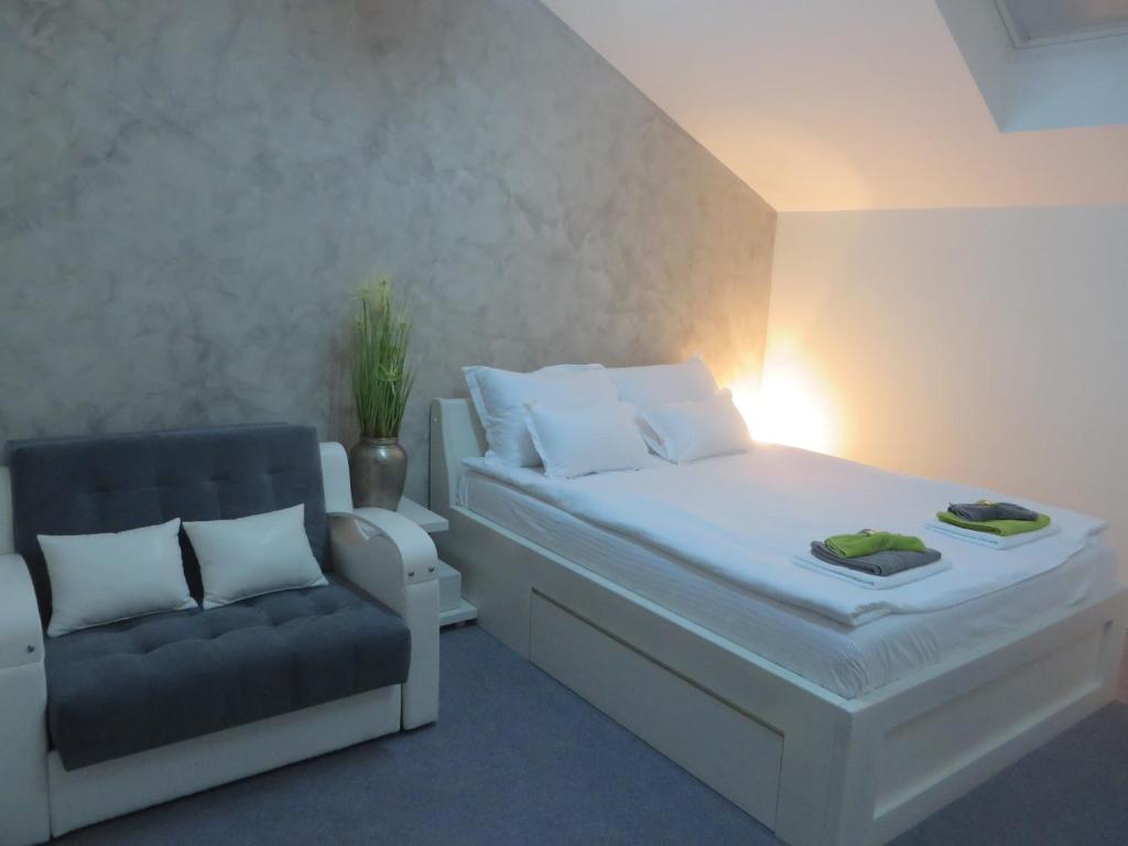 a bedroom with a white bed and a chair at Villa Marija M L in Belgrade