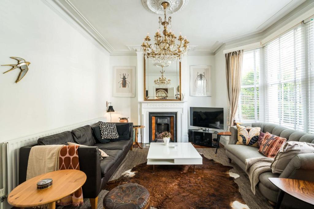 uma sala de estar com um sofá e um lustre em Beautiful 3BD Home Forest Hill South London em Londres