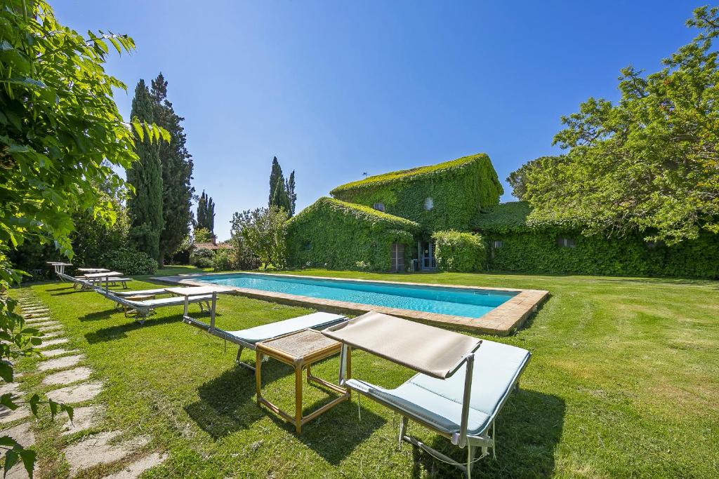 einen Garten mit einem Pool mit Stühlen und einem Haus in der Unterkunft Casale Teresa in Tarquinia