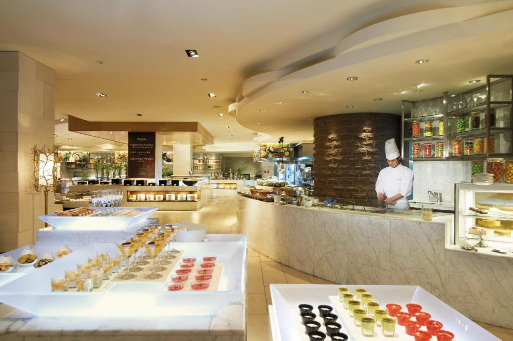 a restaurant with a chef standing behind a counter at Lotte Hotel Ulsan in Ulsan