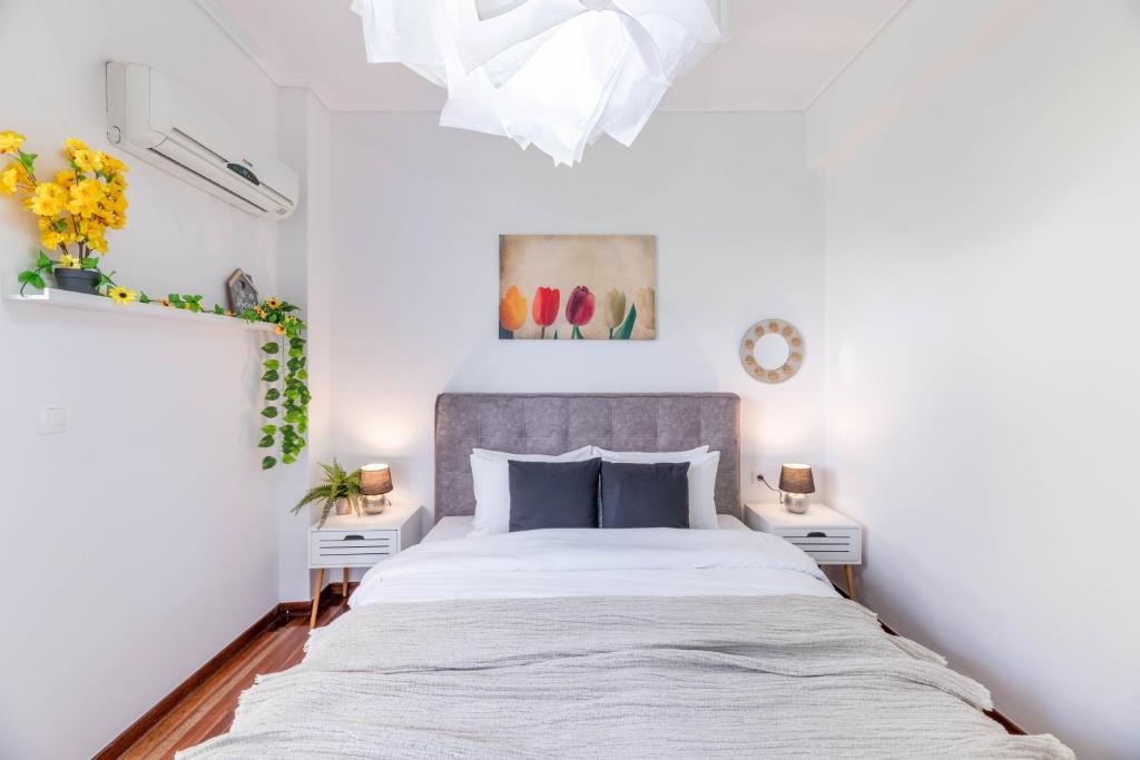 a white bedroom with a large bed and two white tables at Modern Escape Near Riviera & Niarchos Foundation! in Athens