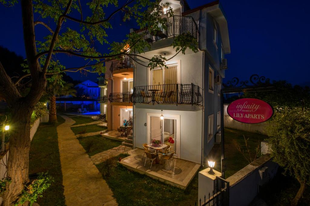 een wit gebouw met een tafel ervoor in de nacht bij Infinity Lily Apartments in Fethiye