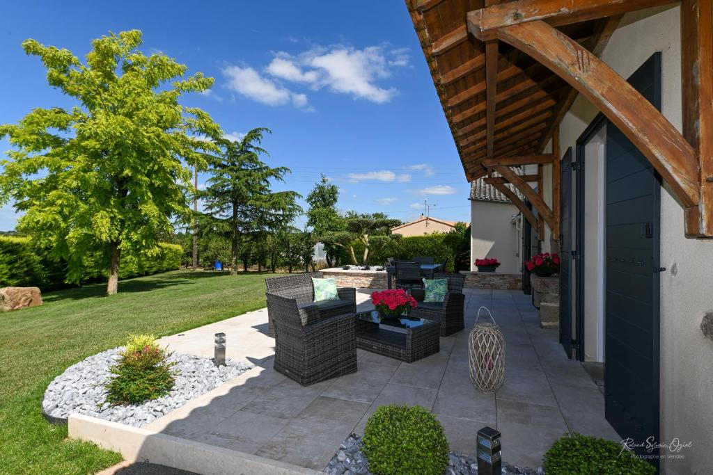een patio met stoelen en tafels op een tuin bij Au doux repos in La Gaubretière