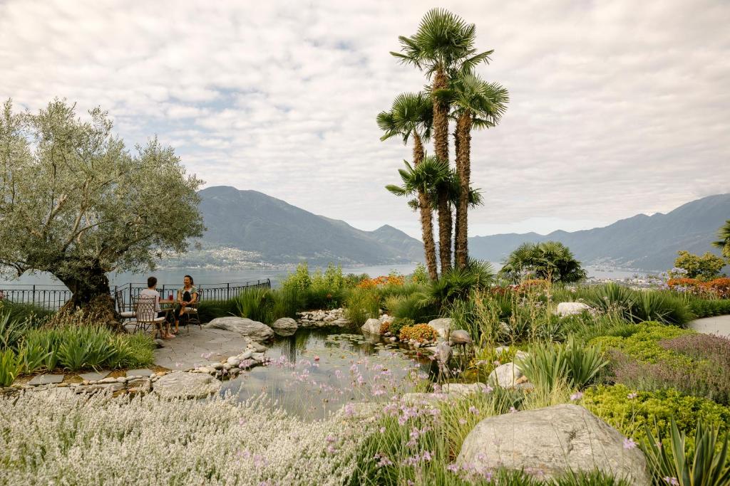 a garden with palm trees and a pond at CHIVA SUN well-being Gästesuite in Brione sopra Minusio