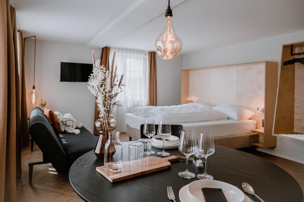 a room with a table with wine glasses and a bed at Hotel Müllers Self-Check-In in Arbon