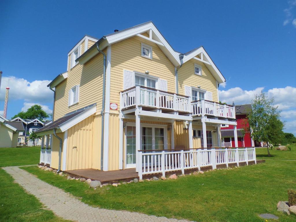 a large yellow house with a porch and balcony at Strandpark Sierksdorf H073 in Sierksdorf