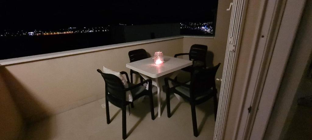 uma mesa e cadeiras numa varanda com uma vela em Sandy Beach apartment em Pag