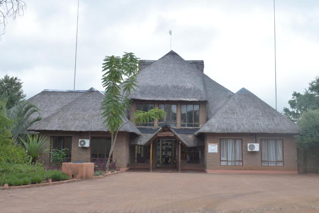 a house with a thatched roof and a palm tree at Copacopa Lodge and Conference Centre in Punda Maria