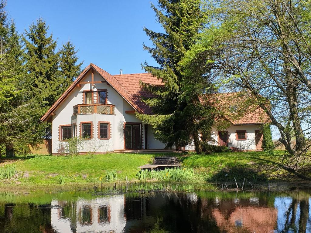 a house with a pond in front of it at Onufrowy Dworek in Ruciane-Nida