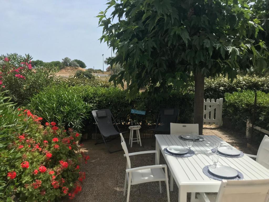 une table et des chaises blanches sous un arbre dans l'établissement Superbe logement en bord de mer, au Cap d'Agde