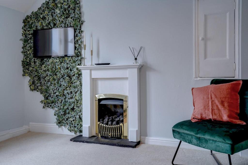 a living room with a fireplace and a green chair at Stunning designer apartment in an ancient building in Norwich