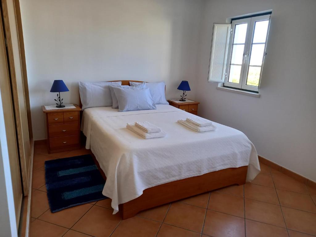 a bedroom with a large white bed with two night stands at T2,Casa Sol e Mar 50464/AL in Vila Nova de Milfontes