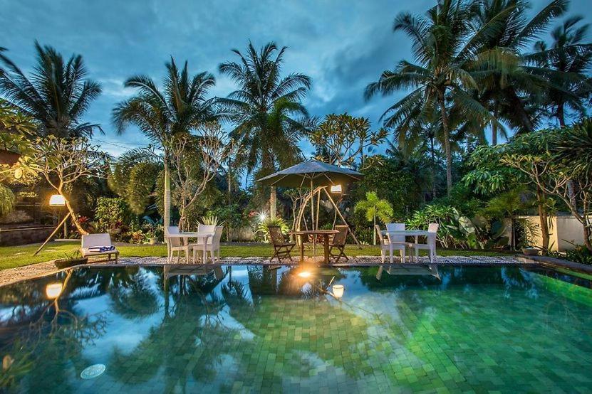 een zwembad met 2 stoelen en een prieel bij The Radian Villa Ubud in Ubud