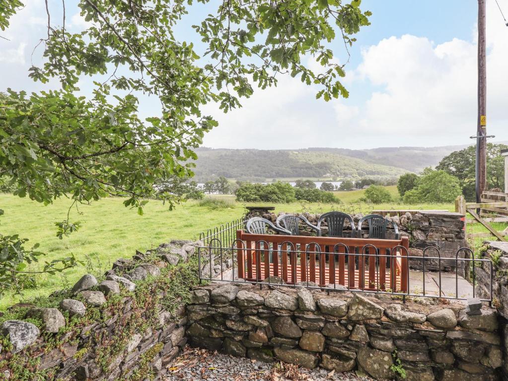 a stone wall with a bench in a field at 1 Lake View in Coniston