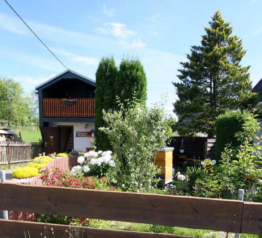 a garden in front of a house with a wooden fence at Ferienhaus beim Imker in Marienberg