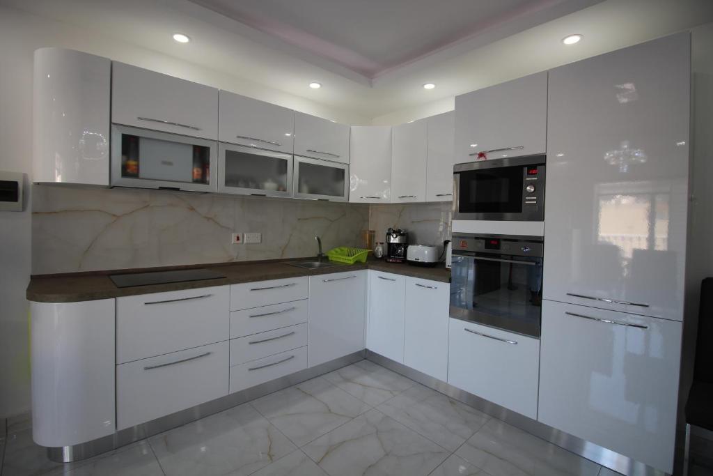 a white kitchen with white cabinets and appliances at BF RESIDENCE in St Paul's Bay