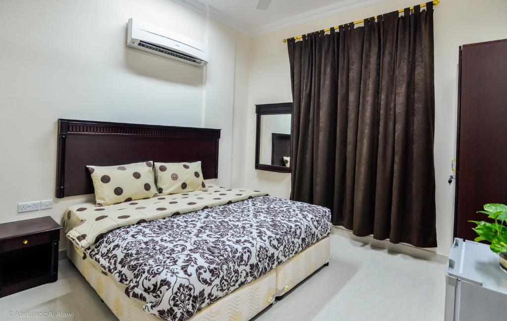 a bedroom with a bed and a window at Al Jumhour Hotel Apartments in Sur