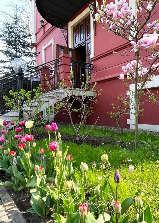 różowy dom z kwiatami przed nim w obiekcie Willa Impresja Hotel i Restauracja w mieście Pabianice