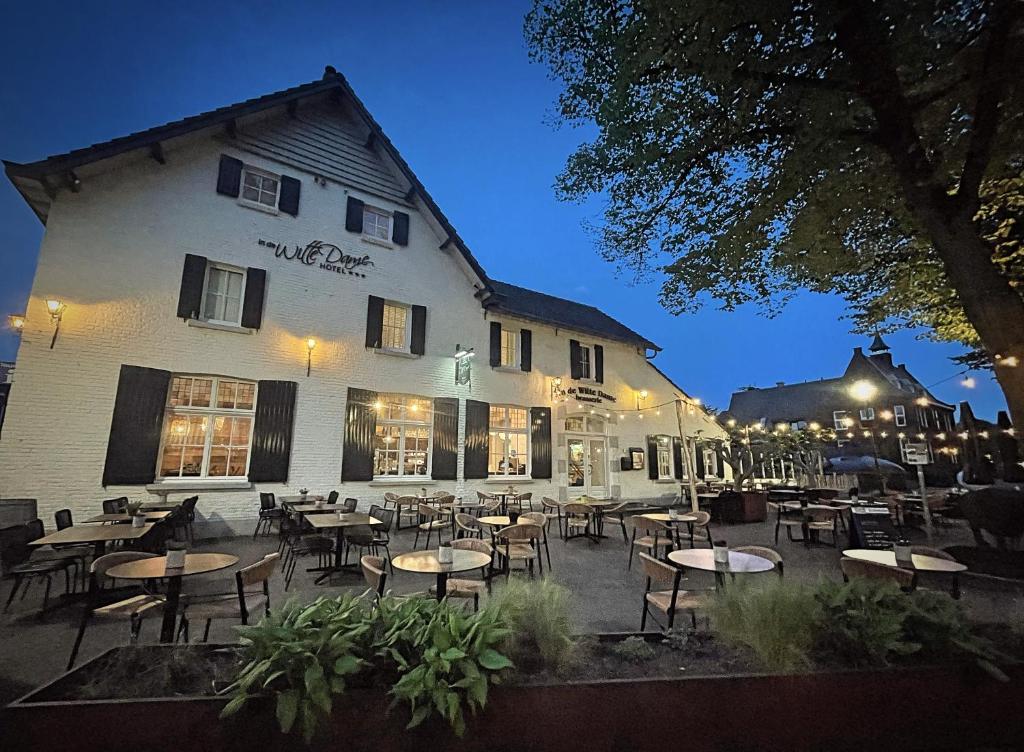 ein Restaurant mit Tischen und Stühlen vor einem Gebäude in der Unterkunft In de Witte Dame Hotel Bar Kitchen Apartments in Grubbenvorst