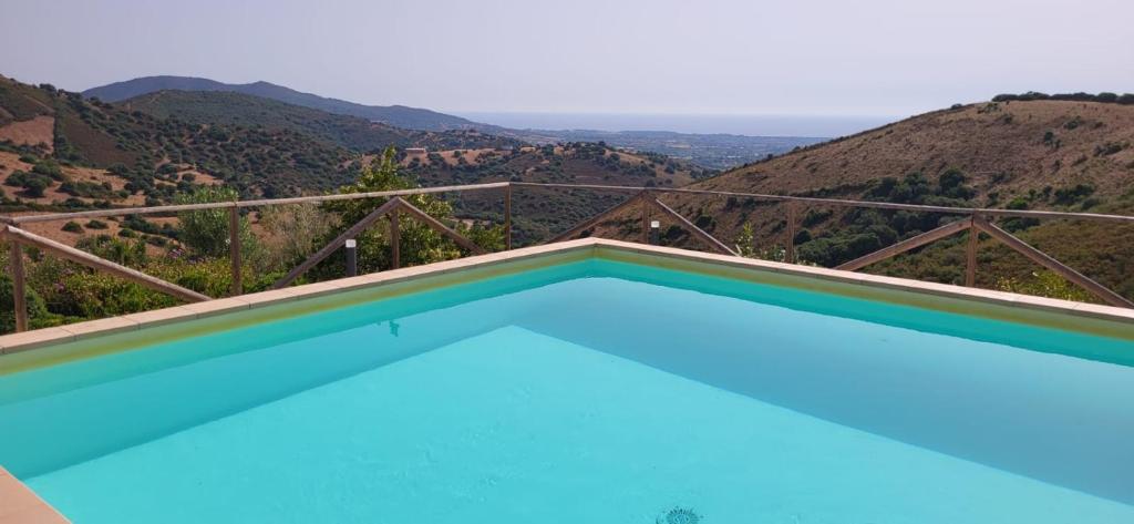 a swimming pool with a view of the mountains at Azienda Agrituristica La Janna di la Faj in Budoni