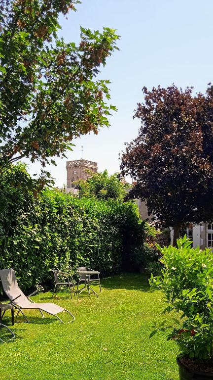 a park with two chairs and a table in the grass at Les Clés du Parc in Combrand