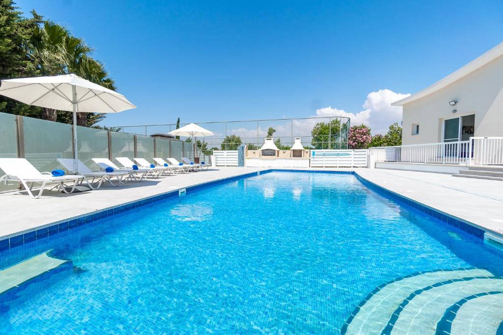 a swimming pool with chairs and an umbrella at Villa Amelia by Ezoria Villas in Perivolia