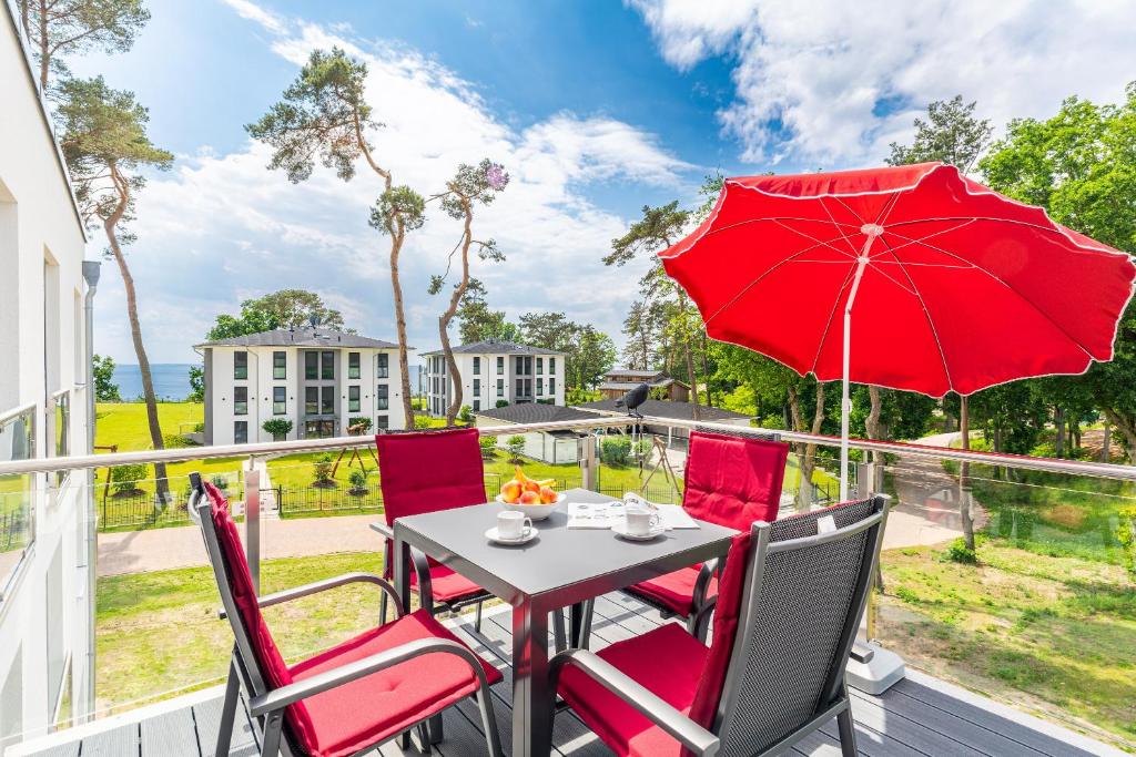 a table and chairs with a red umbrella on a balcony at Apartment "Marco Polo" - Haffresidenz in Garz-Usedom