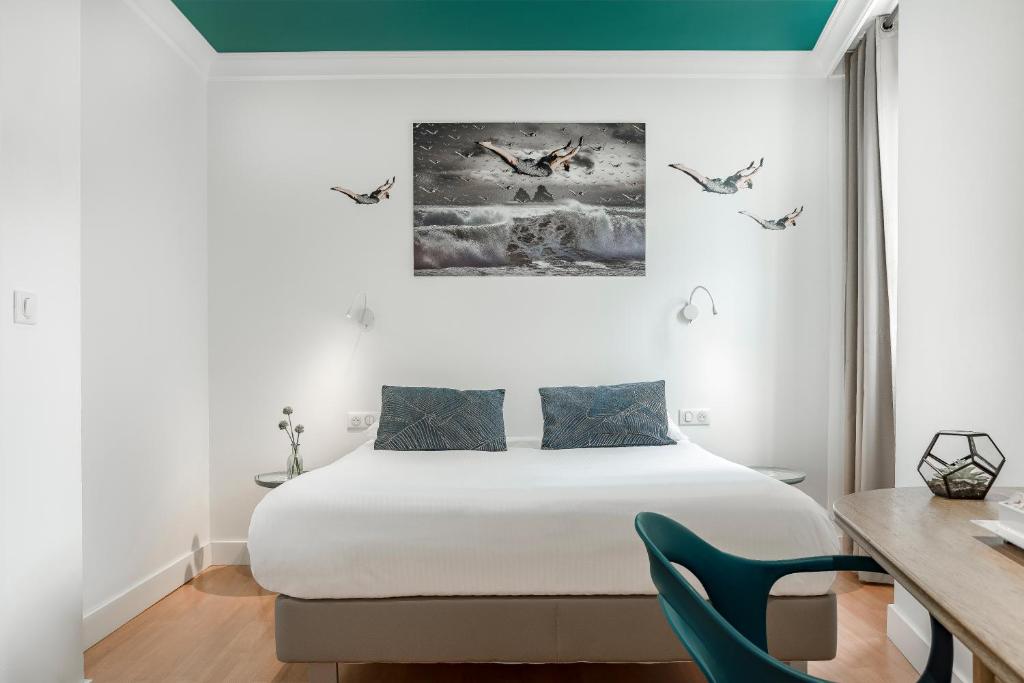 a bedroom with a bed and a desk with a chair at The Originals Boutique, Grand Hôtel de la Gare, Toulon in Toulon