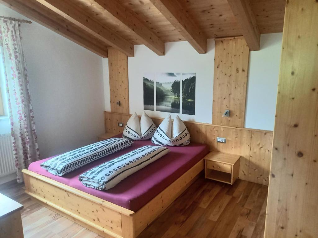 Cama grande en habitación con paredes de madera en Pferdehof Ansteingut, en Sluderno