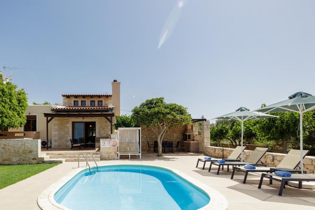 una piscina con sillas y una casa en Stavromenos Villas - Private Pools & Seaview - 500m from Beach, en Stavromenos
