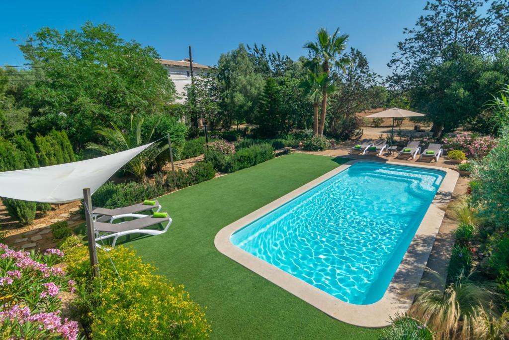 einen Pool in einem Garten mit Stühlen und einem Sonnenschirm in der Unterkunft Cas Pilot in Santa Maria del Camí