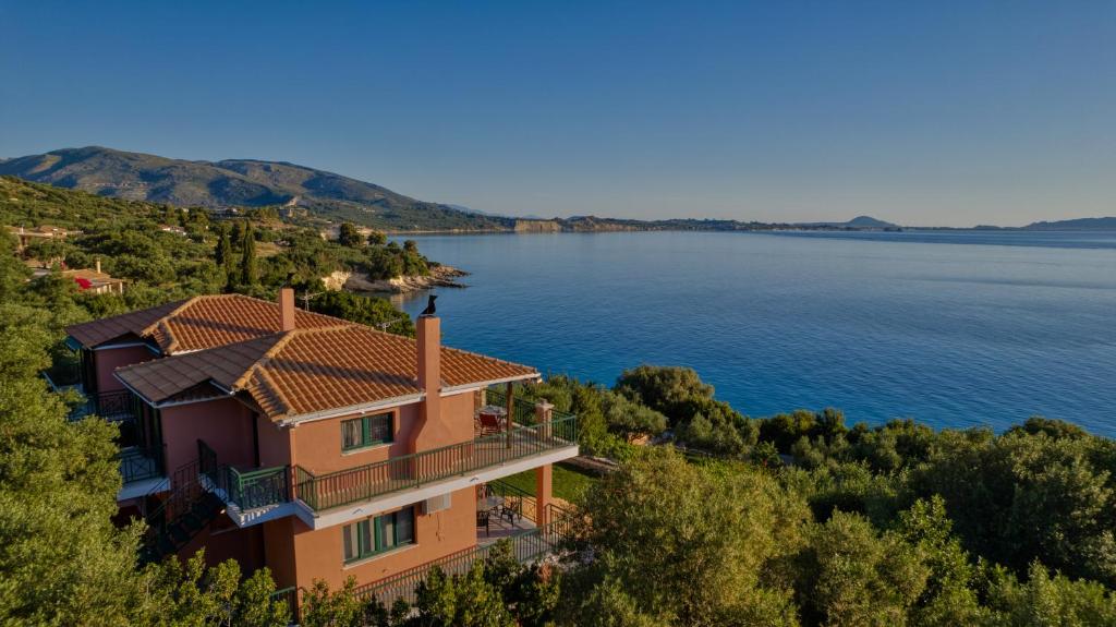 a house on a hill next to a body of water at Anatoli Apartments in Marathias
