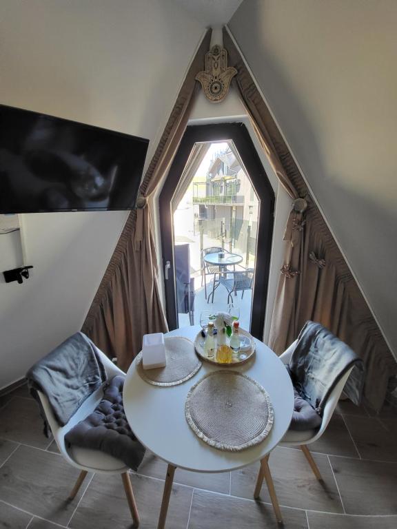 een tafel en stoelen in een kamer met een raam bij Apartman Krnjajic Diamond Hill in Divčibare