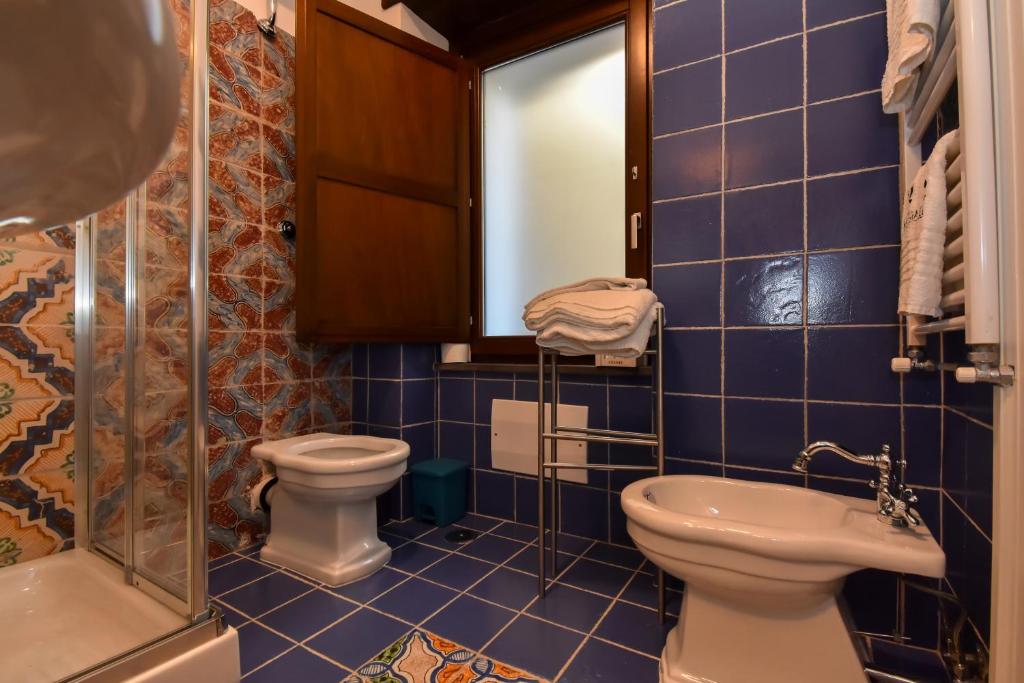 a blue tiled bathroom with a toilet and a sink at Bella Baia Relais in Maiori