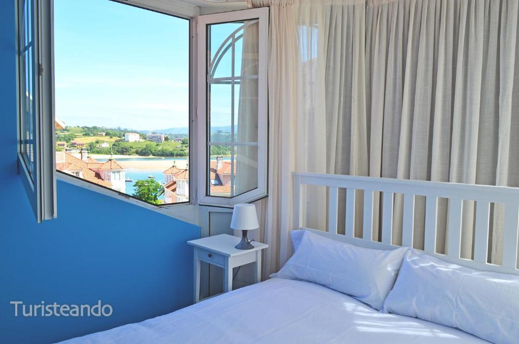 um quarto com uma cama e uma grande janela em Brisa Marinera - para quienes huyen de lo común em San Vicente de la Barquera