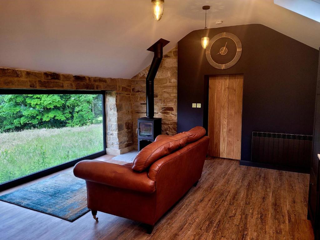 a living room with a leather couch and a fireplace at Underhill Coach House in Whitby