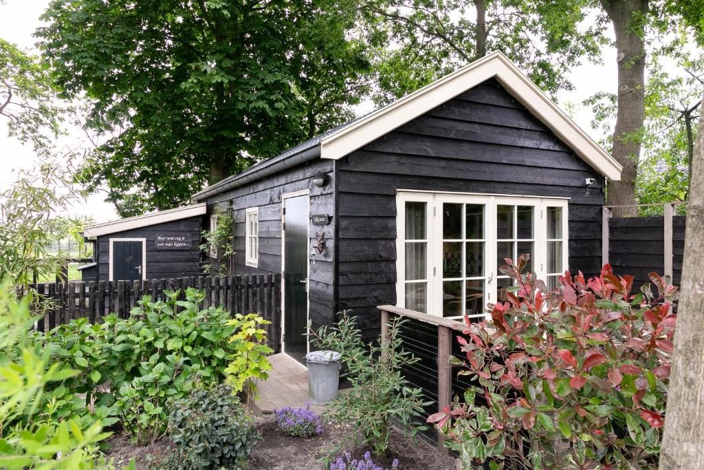 uma pequena casa preta num jardim em Cottage 'Onder de boompjes' em Oostwoud