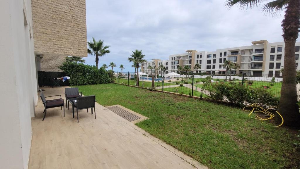 a patio with a table and chairs and a lawn with buildings at Plage des nation 2 bedroom 100 mètre to the beach with huge pool 