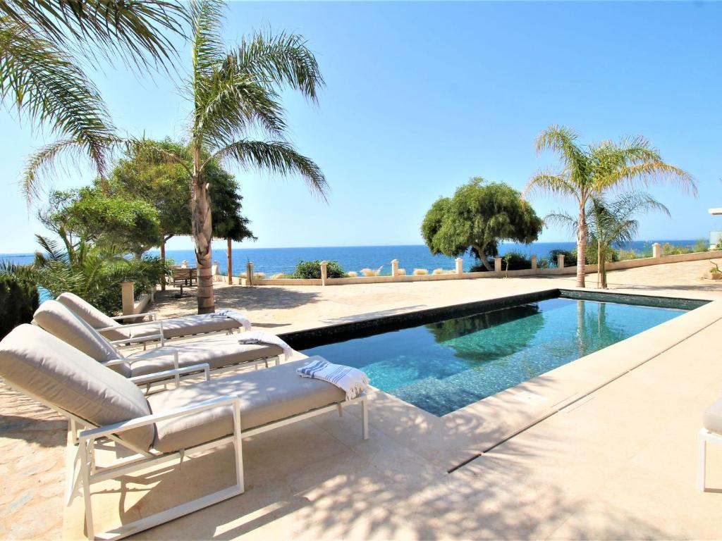 a swimming pool with lounge chairs and the ocean at Holiday Home Casa Taty by Interhome in Villajoyosa