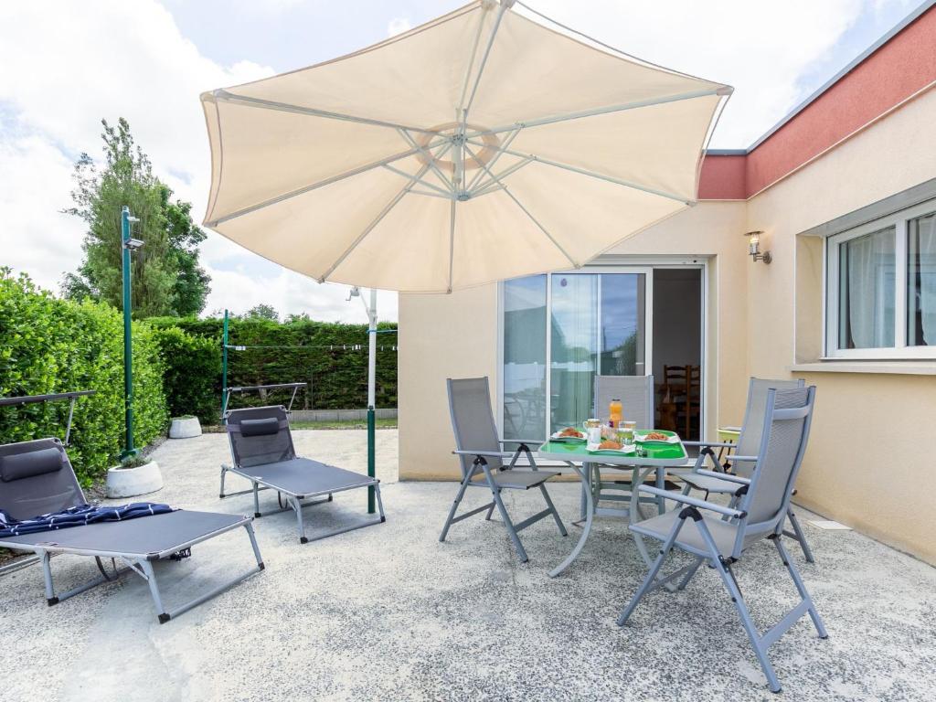 eine Terrasse mit einem Tisch, Stühlen und einem Sonnenschirm in der Unterkunft Holiday Home Ty Fañch - KER227 by Interhome in Kerlouan