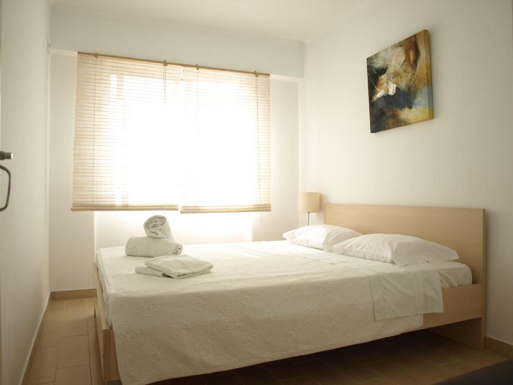 a bedroom with a large white bed with a window at Caparica Beach House in Costa da Caparica