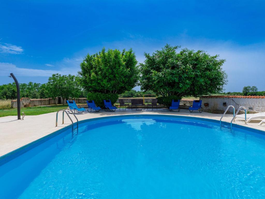 a large swimming pool with blue chairs and trees at Holiday Home Jadranka by Interhome in Muntić